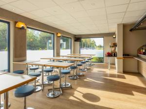 a row of tables and stools in a room with windows at ibis Budget Charleroi Airport in Charleroi