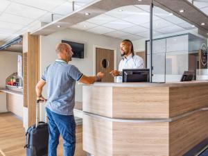 twee mannen bij een receptie in een winkel bij ibis Budget Charleroi Airport in Charleroi