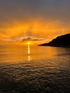 a sunset over the water with the sun setting at karaöz lighthouse bungalow in Kumluca