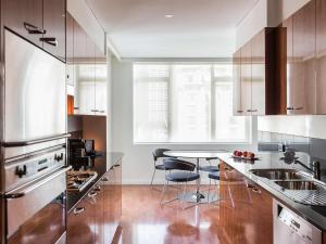 a kitchen with stainless steel appliances and a table at Quay West Suites Melbourne in Melbourne