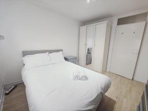 um quarto com uma grande cama branca com duas alianças de casamento em City Airport Apartment em Londres