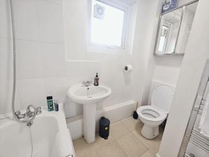 uma casa de banho branca com um lavatório e um WC em City Airport Apartment em Londres