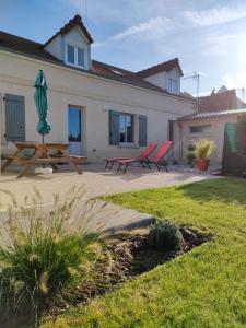 a patio with two chairs and a table and an umbrella at L'intemporelle in Le Crotoy