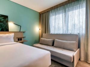 um quarto de hotel com uma cama e uma janela em Novotel BH Savassi em Belo Horizonte