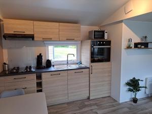 een keuken met houten kasten, een wastafel en een raam bij Chalet Trigano in Lauwersoog