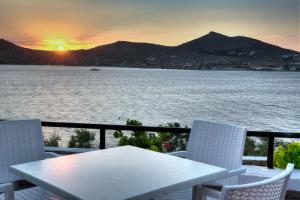 a table and chairs on a balcony with the sunset at Hippocampus Hotel in Naousa
