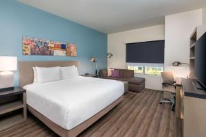 una camera d'albergo con un grande letto e un divano di Hyatt House Orlando Airport a Orlando