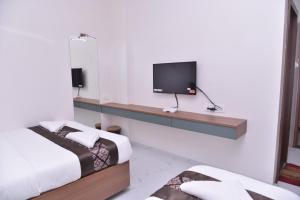 a room with two beds and a tv on a wall at HOTEL D SQUARE . in Shirdi