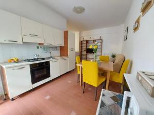 a kitchen and dining room with a table and yellow chairs at Relax Fiorella in Ladispoli