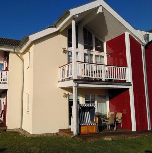 Maison rouge et blanche avec balcon et chaises dans l'établissement Ferienwohnung Strandnest Sierksdorf, à Sierksdorf