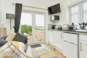 a kitchen with a couch and a kitchen with a window at Little Dell in Newchurch