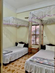 a bedroom with two beds and a window at Nhà nghỉ Minh Hạnh in Hoàng Ngà