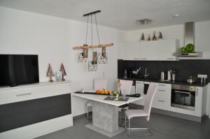 プルツにあるApart van der Heydの白いキャビネット、テーブルと椅子付きのキッチンが備わります。