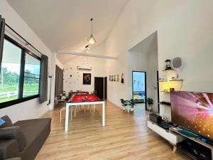 ein Wohnzimmer mit einer Tischtennisplatte und einem TV in der Unterkunft บ้านไออุ่น เขื่อนไม้เต็ง in Ban Na Thom