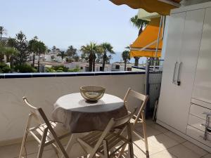 a table and chairs on a balcony with a view at Apartamento con piscina climatizada y vista al mar in San Bartolomé de Tirajana