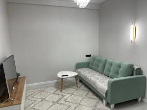 ビシュケクにあるRent Apartmentのリビングルーム(緑のソファ、テーブル付)