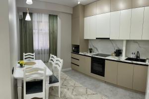 a kitchen with white cabinets and a table and chairs at Rent Apartment in Bishkek