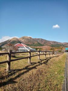 ein Holzzaun auf einem Feld mit Bergen im Hintergrund in der Unterkunft Kurokawa Onsen Besso - Vacation STAY 14733 in Minamioguni