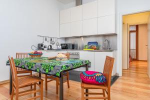 una cocina con mesa y sillas y una cocina con armarios blancos. en Quiet house in a lively area! en Milán