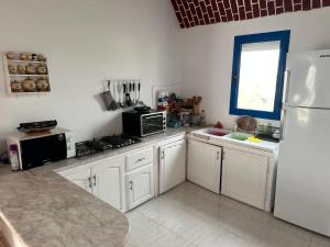 uma cozinha com armários brancos e um frigorífico branco em Appartement MANEL em Mezraya