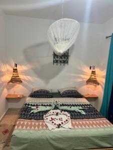 a bed in a bedroom with two lamps and a bedspread at Appartement MANEL in Mezraya