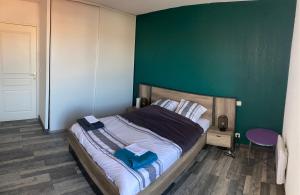 Un dormitorio con una cama con una pared verde. en Appartement 55m² avec vue sur Canigou et Parking, en Rivesaltes
