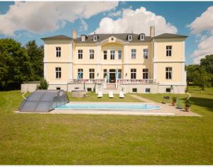 uma casa grande com uma piscina em frente em Schloss Schmuggerow em Schmuggerow