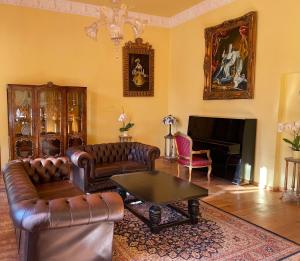a living room with leather furniture and a piano at Schloss Schmuggerow in Schmuggerow +16 photos