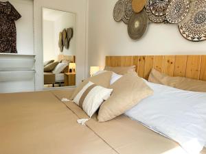 una camera da letto con letto bianco, cuscini e specchio di Villa Rosa Fuerteventura a Corralejo