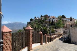 une clôture devant une colline avec des maisons dans l'établissement Casa Sin Numero, an authentic village house, à Comares