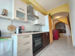 a kitchen with white cabinets and a black stove top oven at La Dimora del Viaggiatore in Jerzu