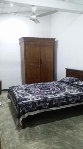 a bedroom with a bed and a wooden cabinet at Rock house kurunegala in Kurunegala