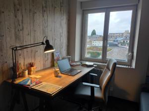 un escritorio con ordenador portátil junto a una ventana en Appartement cosy centre-ville wifi parking en Charleville-Mézières