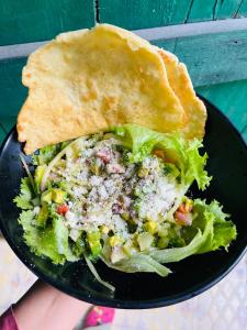 a black plate with a salad and a piece of bread at Bronze Bungalows in Gili Meno