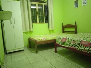 een groene kamer met 2 bedden en een raam bij Pousada Riacho Doce - Curimataí - Buenópolis - MG in Curumatahy