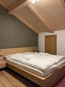 カヴァレーゼにあるMansarda Ciliegio Cavaleseのベッドルーム(白いシーツを使用した大型ベッド1台付)