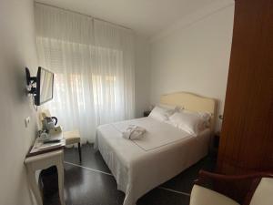 ein kleines Schlafzimmer mit einem weißen Bett und einem Tisch in der Unterkunft Hotel Internazionale in Finale Ligure