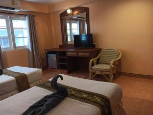 a room with two beds and a desk with a television at Nid Huahin Hotel in Hua Hin