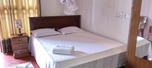 Un dormitorio con una cama blanca con cabecero de madera. en Desitha Family House, en Mirissa