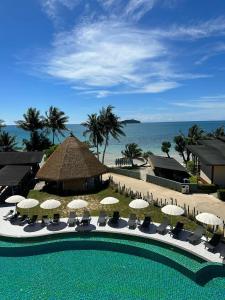 einen Pool mit Stühlen und Sonnenschirmen sowie einen Strand in der Unterkunft Kai Bae Beach Resort Koh Chang in Ko Chang