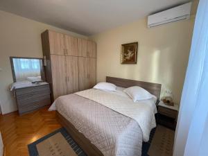 ein Schlafzimmer mit einem Bett, einer Kommode und einem Fenster in der Unterkunft Rooms Krstinić 84 in Palit
