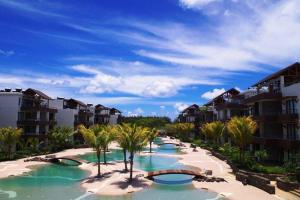 a resort swimming pool with palm trees and buildings at Wonderful Mont Choisy flat, huge lagoon pool in Mont Choisy
