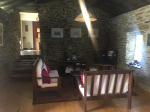a living room with two chairs and a stone wall at Casa de Campo "Quinta do Cadafaz" in Alvarenga