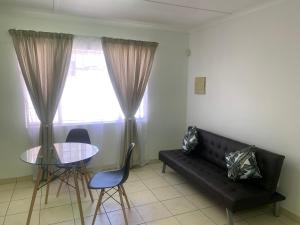 - un salon avec un canapé noir et une table dans l'établissement Pioneerspark Self Catering, à Windhoek