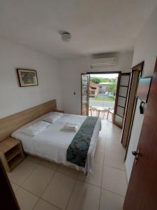 1 dormitorio con 1 cama grande y balcón en Golfinho Plaza Hotel, en Cananéia