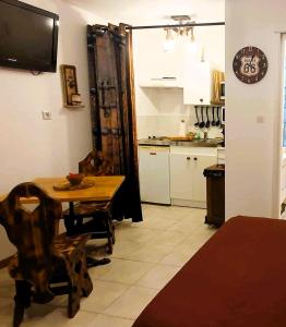 cocina y comedor con mesa y reloj en Studio 19 cosy avec jacuzzi et jardinet privatifs, en Draguignan