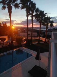 a sunset over a swimming pool with palm trees at Villa Gammarth - Suite N°3 in Gammarth