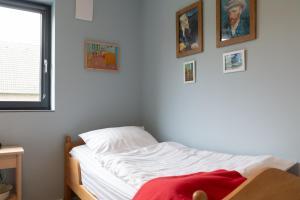 - un lit blanc dans une chambre avec des photos sur le mur dans l'établissement Fewo Eifel Eichen, à Nideggen
