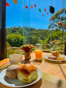 uma mesa com dois pratos de pão e um copo de sumo de laranja em Pousada Olivier da Montanha - Recanto das Águas em Santo Antônio do Pinhal