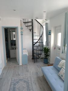 salon z niebieską kanapą i spiralnymi schodami w obiekcie Cozy 1 Bed Retreat - Amlwch w mieście Amlwch
